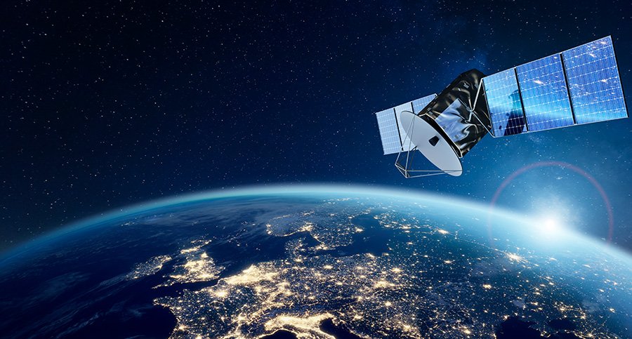 A communications satellite orbits above Earth, with a clear view of Europe illuminated at night. 