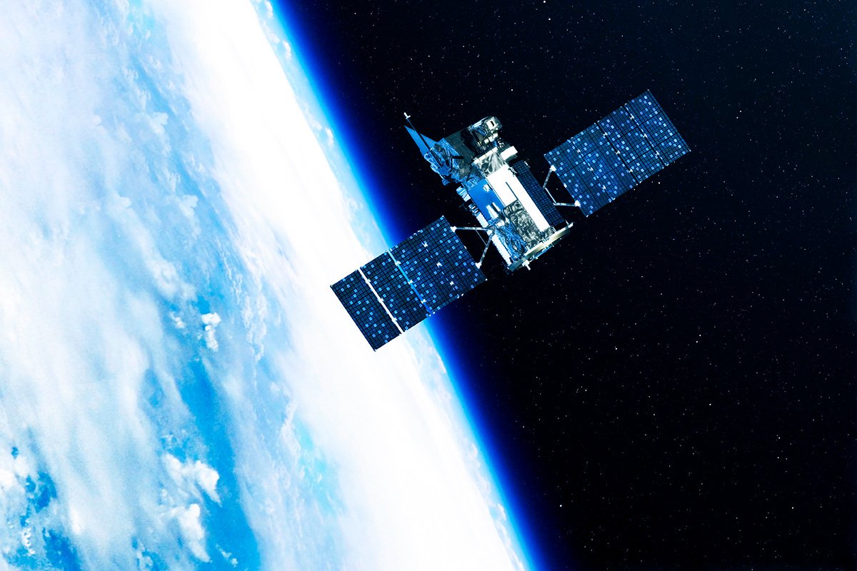 A communications satellite orbits high above Earth against the blackness of space. 