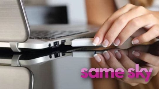 세련된 은색 노트북 포트에 USB 장치를 끼우고 있는 손을 가까이서 촬영한 이미지.