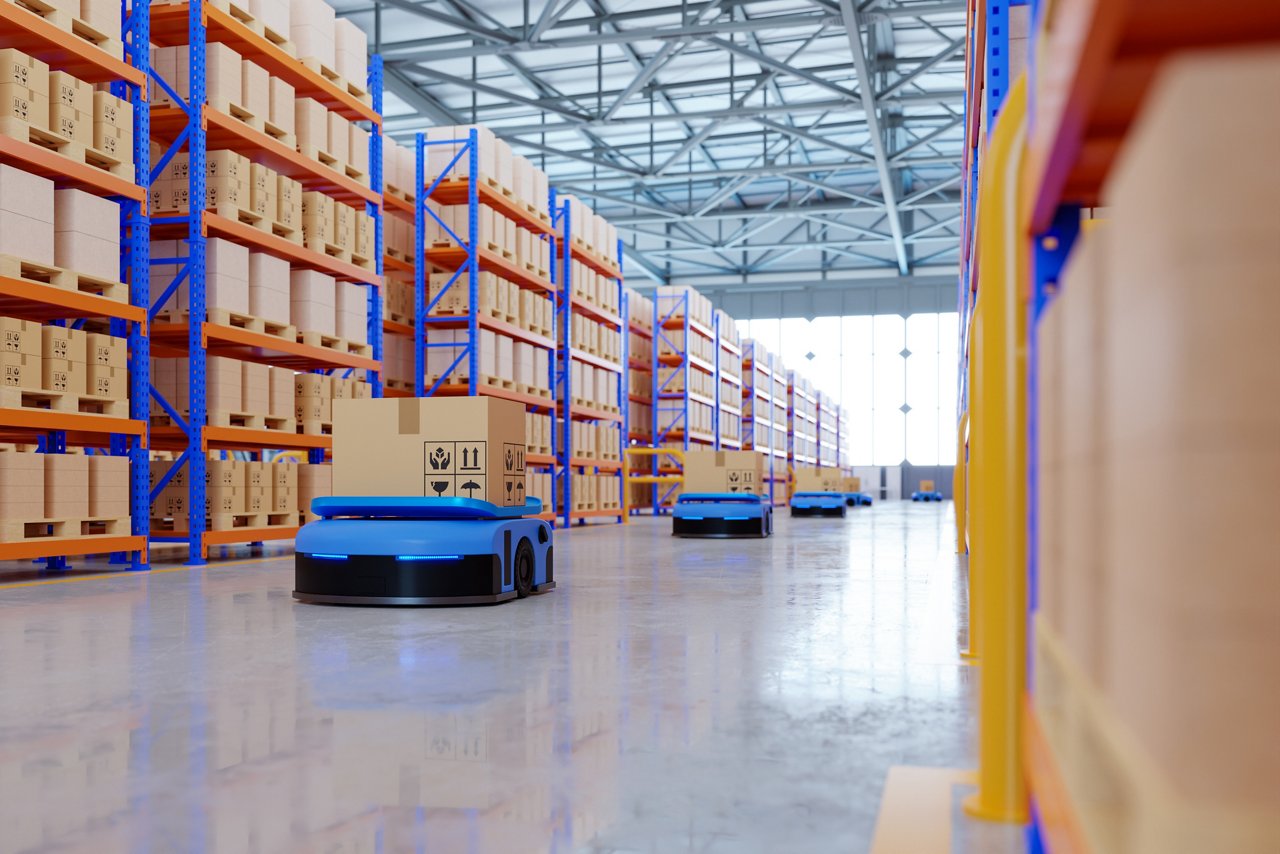 An indoor warehouse filled with tall shelving racks and boxes, with several low-profile autonomous robots moving goods across the polished floor.