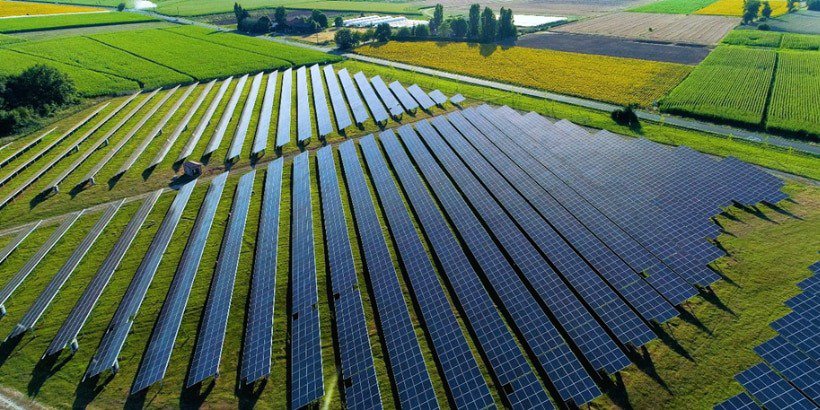 A vast solar farm featuring rows of photovoltaic panels arranged in a geometric pattern
