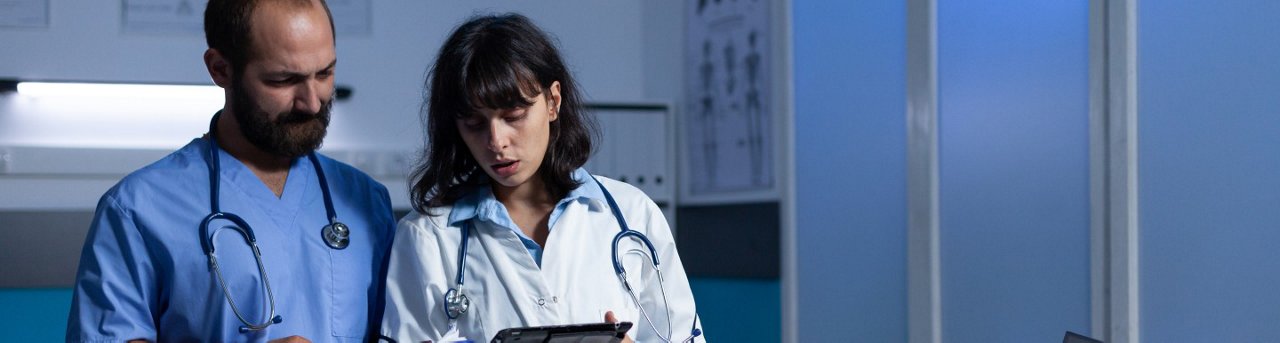 Two medical professionals reviewing clipboard in hospital setting
