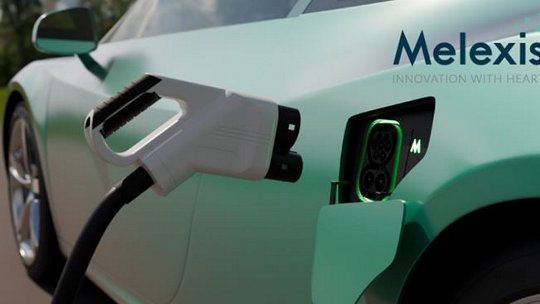 Una vista en primer plano de un coche eléctrico siendo cargado, con el logotipo de Melexis visible y el lema 'Innovación con corazón'.