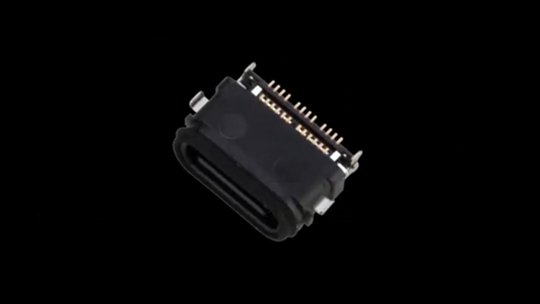 Una vista detallada de un conector USB-C que muestra sus pines y diseño compacto. El conector está situado sobre un fondo negro sólido, destacando su apariencia elegante y funcional.
