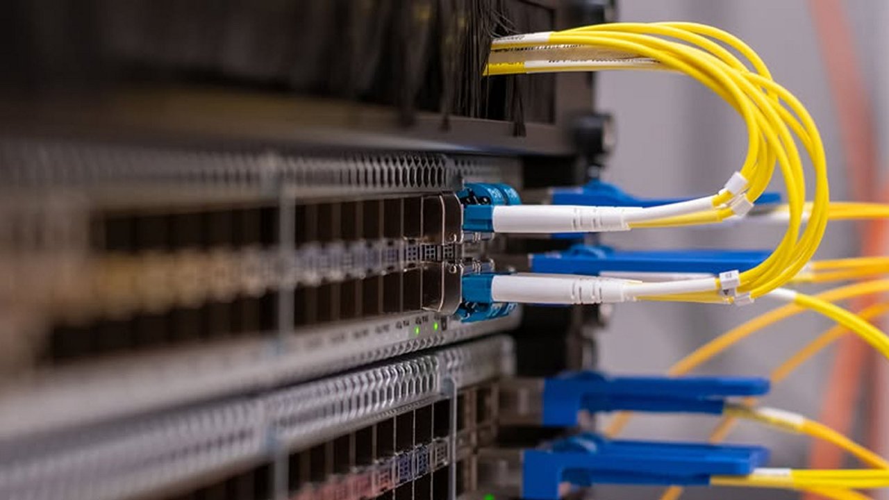 データセンター内のサーバーラックに接続された黄色の光ファイバーケーブルの詳細なビュー。