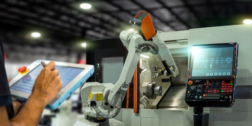 Ein Roboterarm arbeitet in einer hochmodernen Fertigungsumgebung und interagiert mit einer Steuerungskonsole und Maschinen.