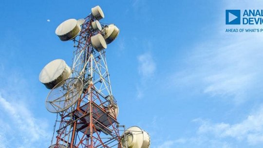 A tall telecommunication tower equipped with multiple satellite dishes and antennas, set against a clear blue sky. 