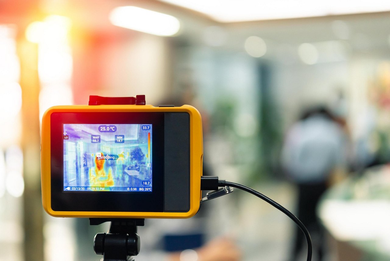 明るく照らされた屋内環境で、ハンドヘルド型熱画像装置が熱の署名を捉える