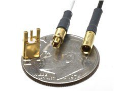 Close-up of miniature gold connectors placed on a coin for scale comparison. 