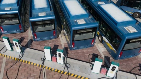 Una flota de autobuses eléctricos azules estacionados en una estación de carga