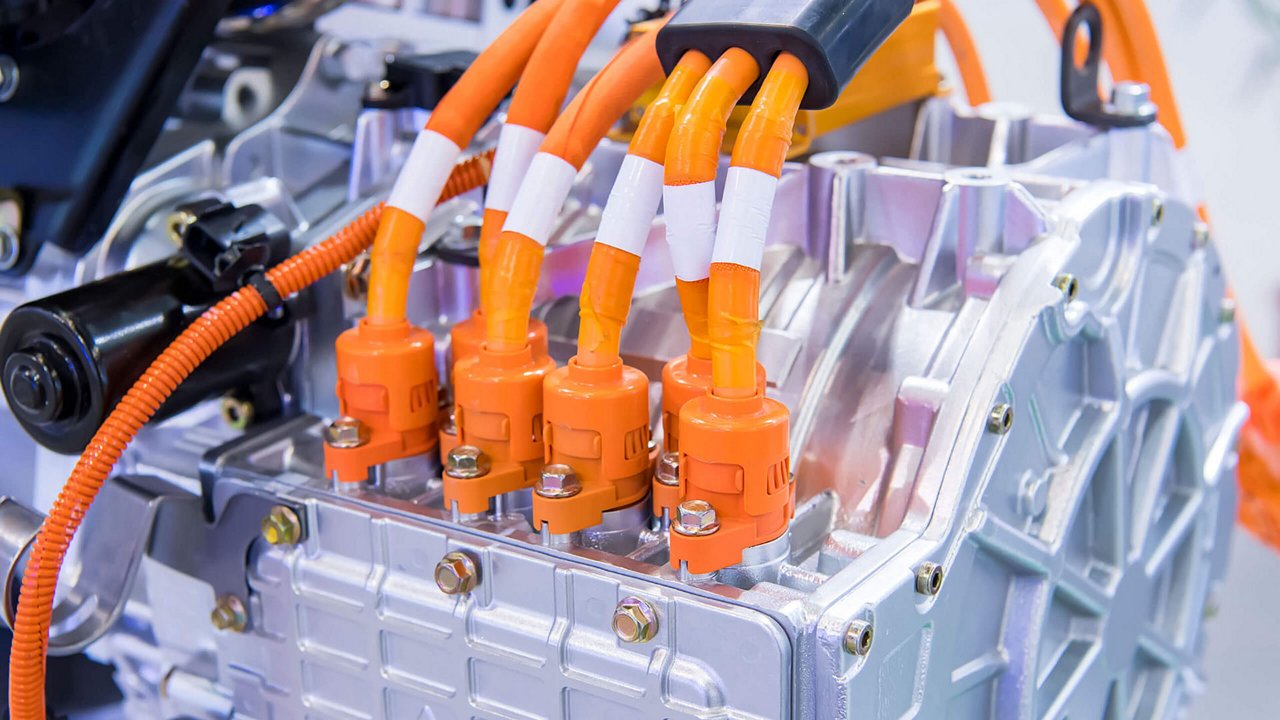 Nahaufnahme eines Elektromotorfahrzeugs, die komplexe metallische Komponenten und leuchtend orangefarbene Verkabelung zeigt.