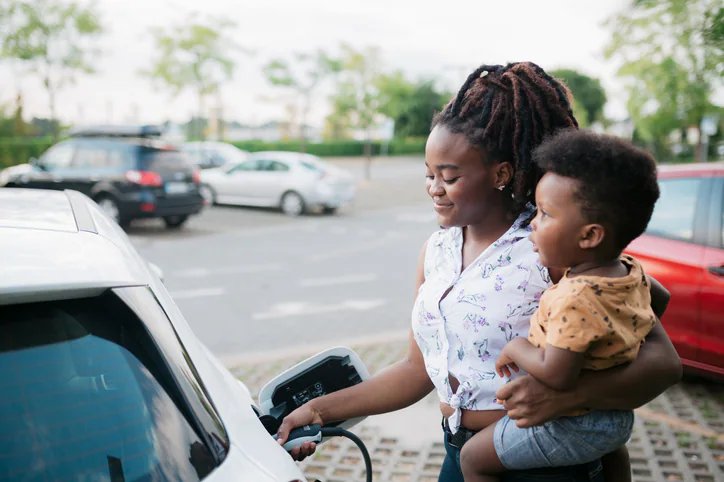 Woman holding child while charging EV car