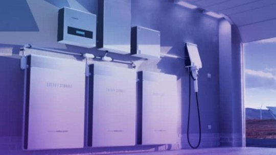 A sleek energy storage system featuring multiple battery units and a charging station is showcased in a futuristic indoor space.