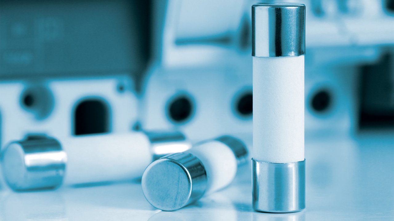 Una vista dettagliata di fusibili elettrici cilindrici con terminali metallici, posizionati su una superficie riflettente.