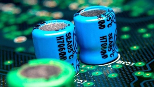 A detailed view of blue capacitors labeled SEA85°C H706CM mounted on a green circuit board.