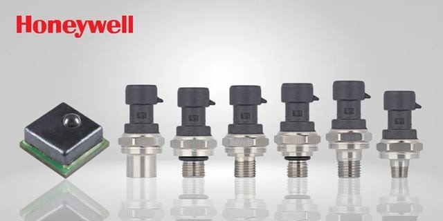 A lineup of Honeywell pressure sensors displayed against a neutral gray background. The image features six cylindrical sensors with metallic bases and black connectors, alongside a square sensor module. 