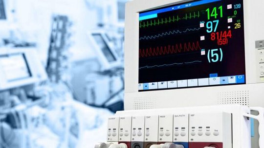 Monitor medico che mostra i segni vitali, inclusi frequenza cardiaca, frequenza respiratoria e altri dati, in un contesto ospedaliero.