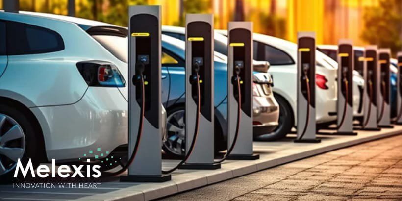 夕日が沈む中、現代的な充電ステーションに並んで停められた電気自動車の列