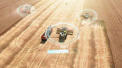 Aerial view of multiple automated harvesters operating in a golden wheat field. 