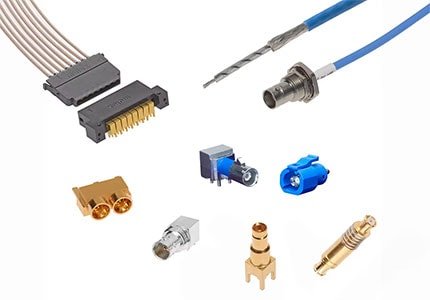 A collection of electronic connectors and cables displayed on a white background. The assortment includes gold-plated connectors, fiber optic cables, and pin headers. The image highlights various connector types used in electronic and communication devices.