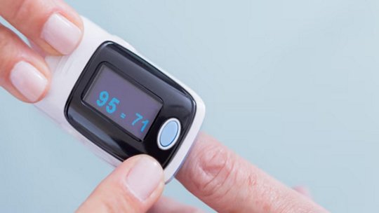 Person using a pulse oximeter on a finger, displaying a reading of 95-71.