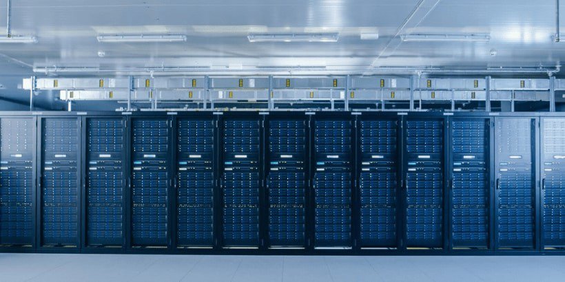 Un centro de datos amplio y de alta tecnología con filas de bastidores de servidores iluminados con luces LED azules.