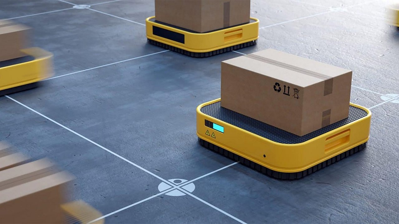 Piattaforme robotiche gialle spostano scatole di cartone su un pavimento di magazzino contrassegnato da una griglia.