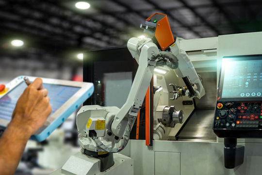 A robotic arm is actively working on a CNC machine in a modern industrial setting. 