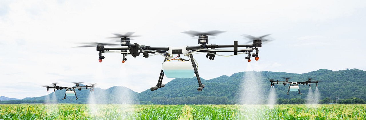 A group of drones is shown spraying crops in a lush green agricultural field.