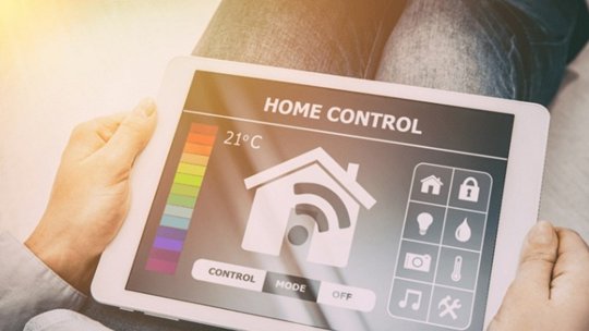 人がスマートホーム制御インターフェースを表示するタブレットを持っている