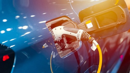 Close-up of an electric vehicle being charged using a yellow cable