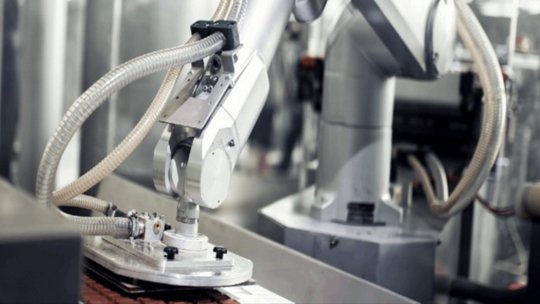 A close-up of a robotic arm equipped with suction technology operating in a modern industrial factory