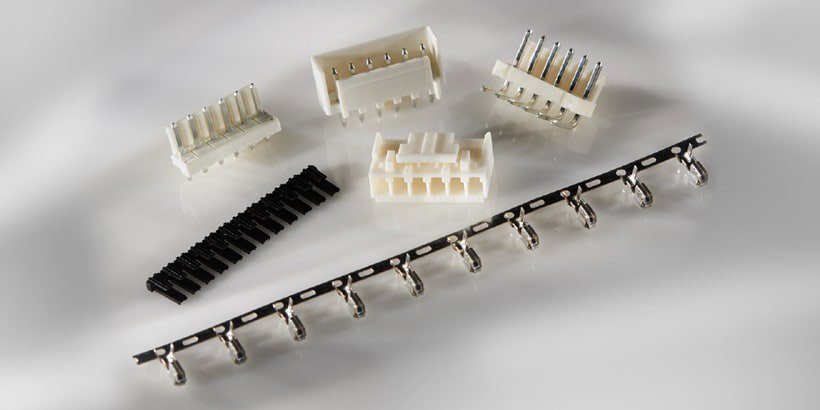 Una collezione di connettori elettrici e componenti metallici esposta su una superficie neutra.