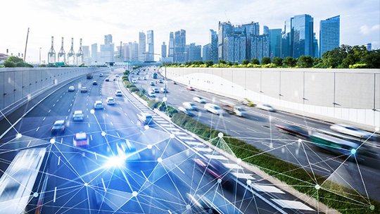 A bustling urban highway with fast-moving vehicles is set against a modern city skyline. 