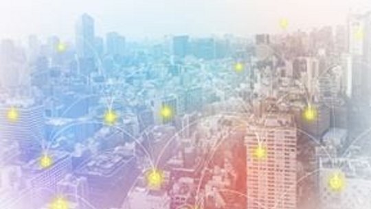 高層ビルと広がるスカイラインが特徴の都市景観に、光り輝くデジタルネットワークノードが重ねられたイメージです。この画像は、接続性と現代的なテクノロジーの感覚を伝えています。カラーパレットは青、赤、白の柔らかなグラデーションが使用されており、未来的な雰囲気を醸し出しています。