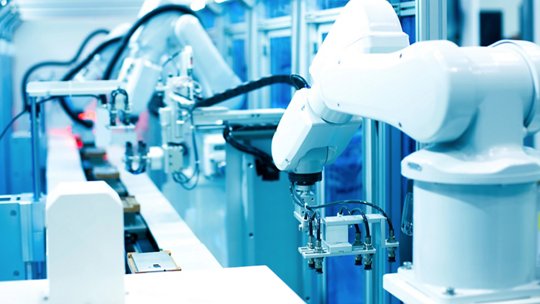 Una vista de cerca de brazos robóticos operando en un entorno de fabricación automatizada de alta tecnología.