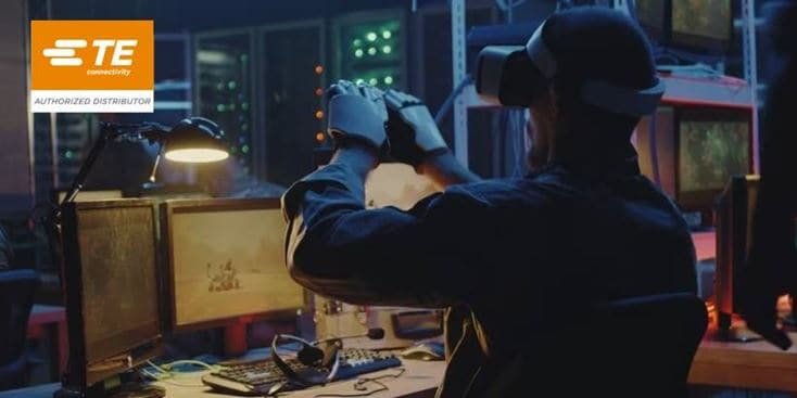 Un hombre que lleva un casco de realidad virtual y guantes interactúa con un entorno digital en un espacio de trabajo tecnológico con poca iluminación.