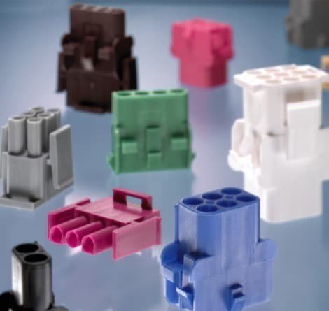 A variety of electrical connectors in multiple colors, including blue, pink, green, and white, are displayed on a reflective surface