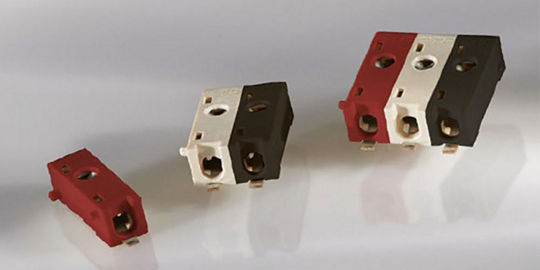 A set of electrical connectors displayed on a neutral surface. The connectors are shown in three colors: red, white, and black, with varying sizes.