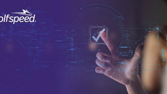 一个未来感十足的数字界面，以发光的对号为特色，映衬在蓝色背景之上。Wolfspeed 的标志显著地显示在左上角。 一只手与界面互动，暗示着创新和科技。情景传达出一种现代化、高科技的氛围。