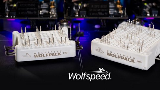 两款Wolfspeed Wolfpack功率模块，PKM和GM2，展示在一个高科技环境中，背景有点亮的组件。