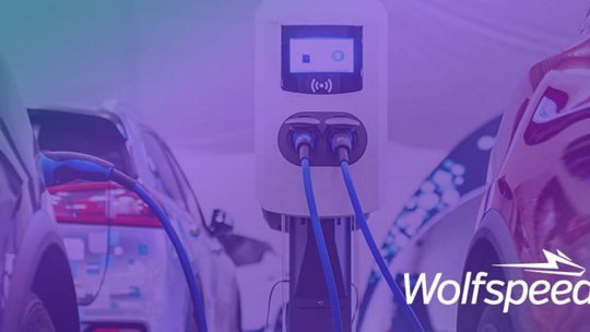 A modern electric vehicle charging station is prominently displayed between two cars in a clean, futuristic setting. 